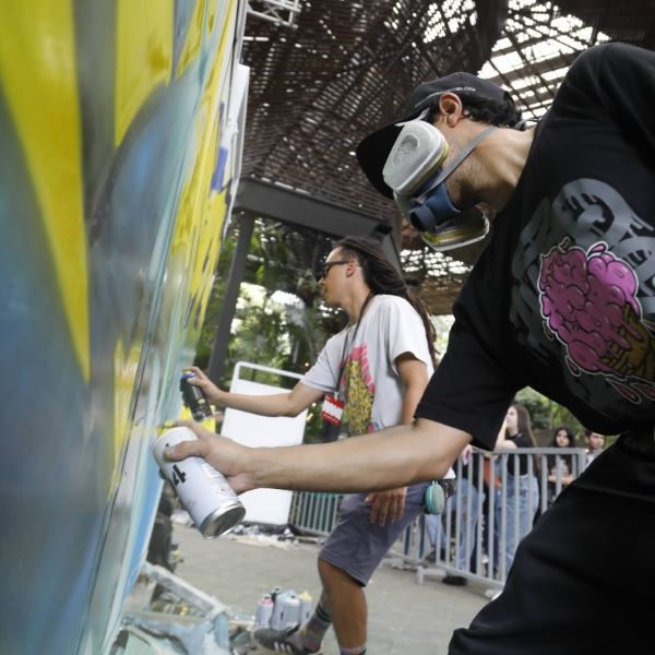 Jóvenes pintando un mural con aerosoles. 